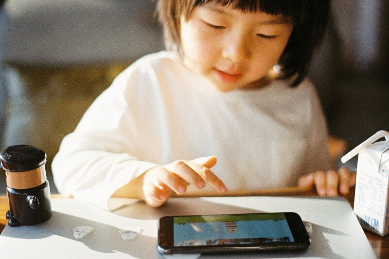 child playing a video game on phone; concept of becoming a victim of cyberattacks