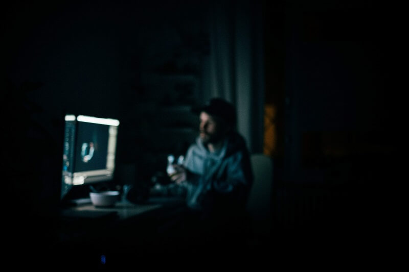 a person sitting at his computer during the night